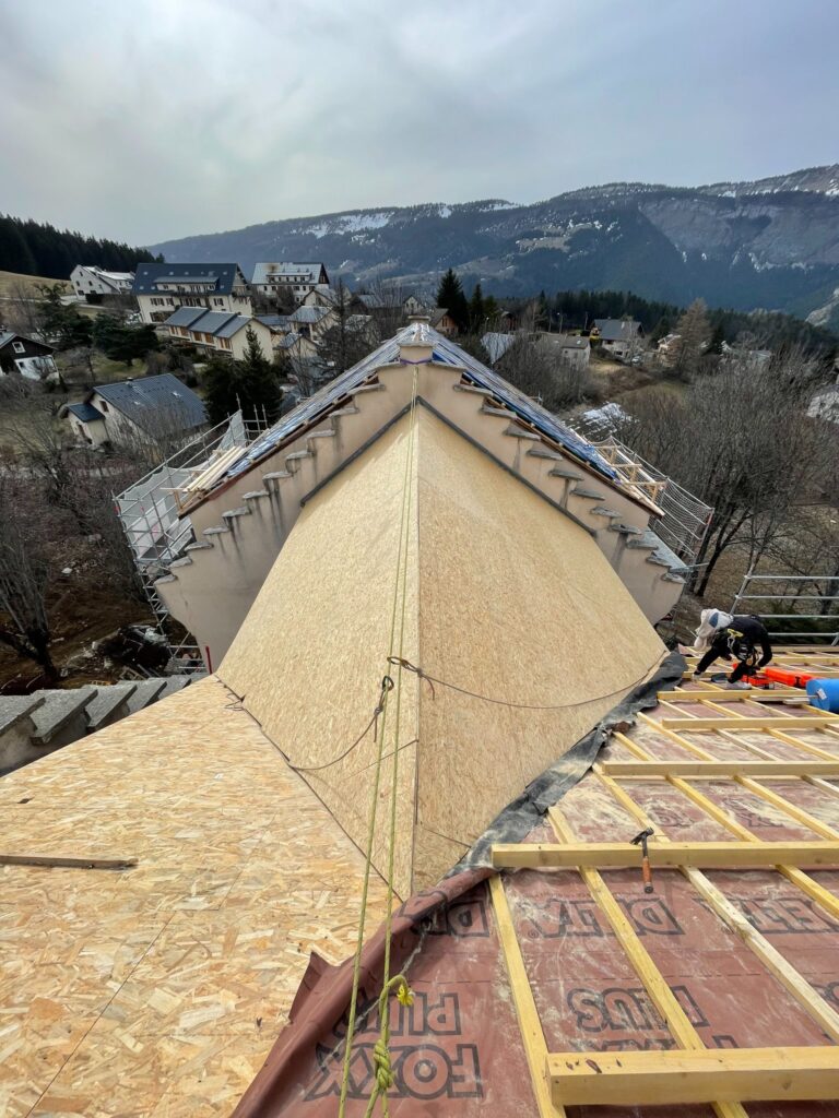 Chantier de Toiture : Installation de Panneaux OSB en Montagne Toiture en construction avec panneaux OSB et membrane Delta Foxx Plus face à un paysage de montagne enneigé.